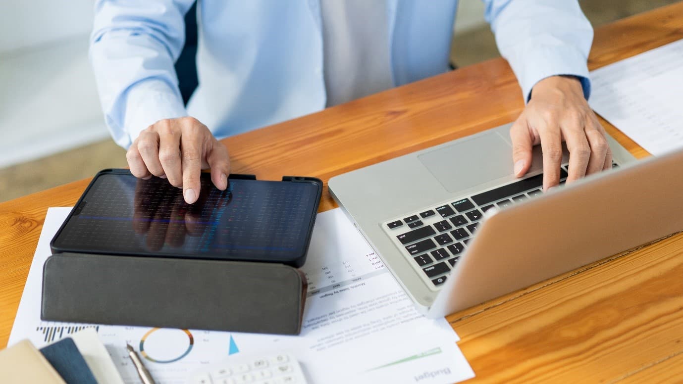 Person at desk with tablet and laptop