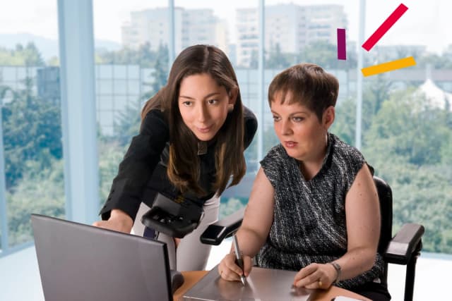 Two women at desk looking at computer