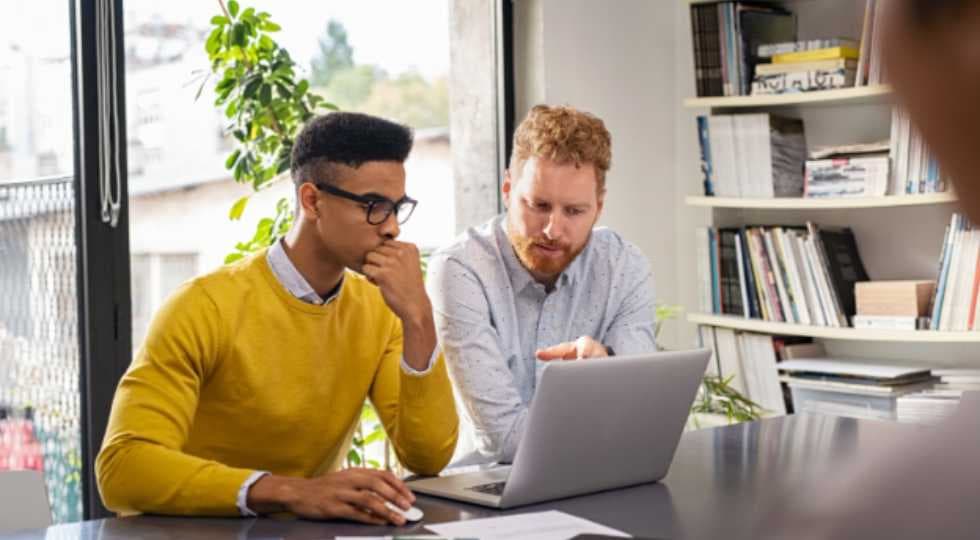 Men at desk pointing at computer