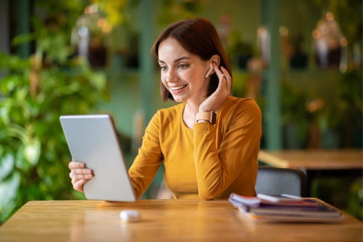 Woman in yellow shirt with airpods and tablet