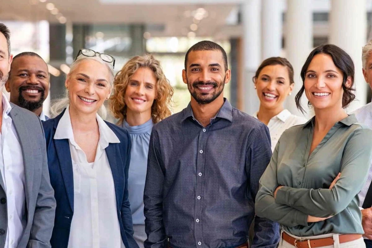 A diverse group of seven smiling professionals, standing together in an office setting